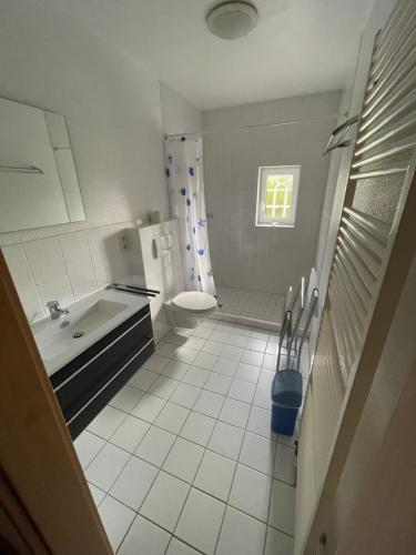 a white bathroom with a sink and a toilet at Ferienwohnungen Am Mühlenhügel in Stedesdorf