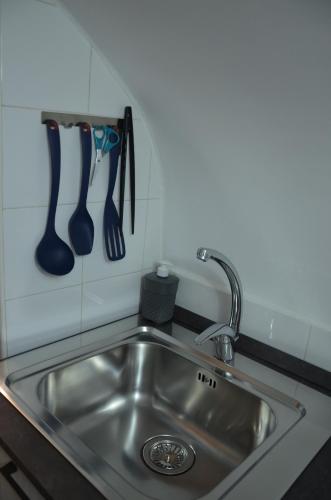 a kitchen sink with utensils hanging on a wall at La maison de Rose in Ostuni