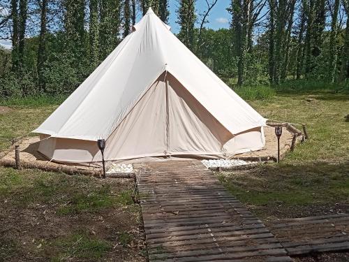Plouray的住宿－tente nature，田野上的白色帐篷,设有木制走道