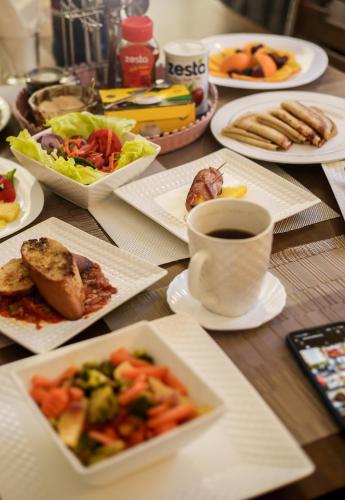 a table with plates of food and a cup of coffee at El Tessa garden/serviced apartment in Kisumu