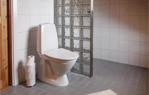 a bathroom with a toilet and a tiled wall at Nice Home In Simrishamn With Kitchen in Simrishamn