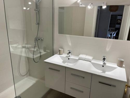 ein weißes Bad mit einem Waschbecken und einer Dusche in der Unterkunft Superbe T3 L’Illiade - Plages 3’ à pieds - Parking in Juan-les-Pins