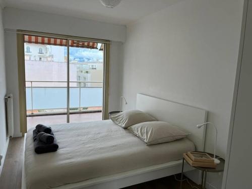 a bedroom with a bed with a large window at Superbe T3 L’Illiade - Plages 3’ à pieds - Parking in Juan-les-Pins