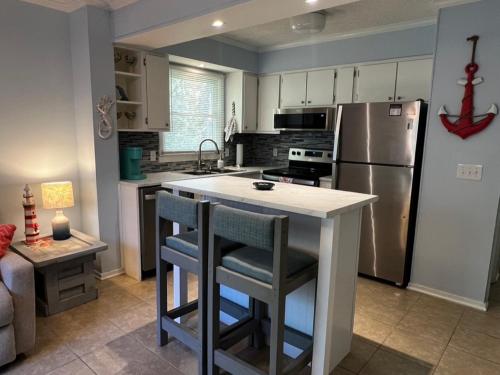 eine Küche mit einem Kühlschrank und einer Theke mit 2 Barhockern in der Unterkunft C Level Condo in Myrtle Beach