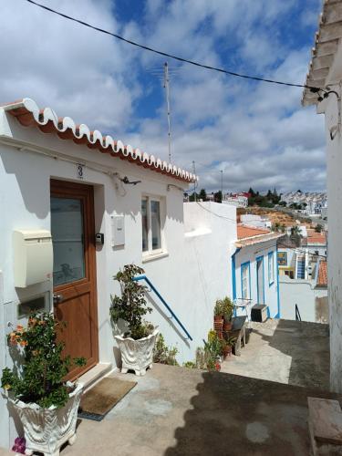 a white house with a wooden door and some plants at Ferragood House - Historic Center in Ferragudo