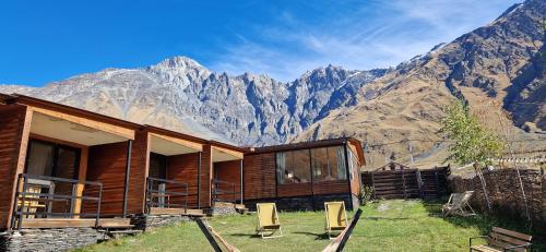 a log cabin with mountains in the background at Kazbegi Cottages in Stepantsminda