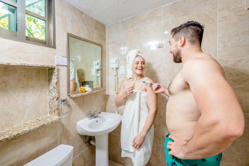 a man and a woman in a bathroom brushing their teeth at Hacienda Inn in Mérida