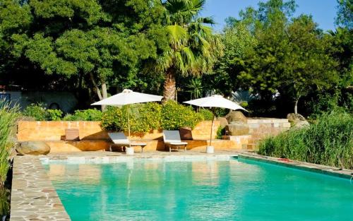 a swimming pool with two umbrellas and two chairs and a table at Herdade da Negrita in Santo Aleixo