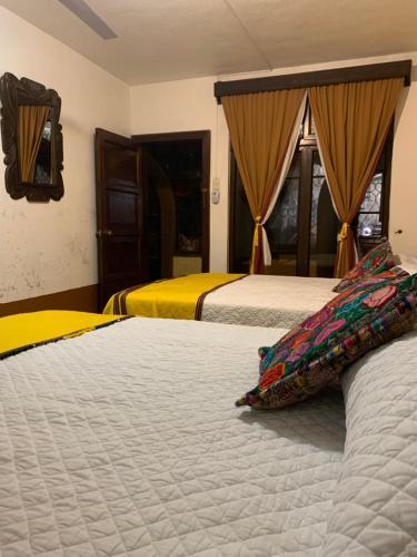 twee bedden in een kamer met geel en wit bij Hotel Posada Don Valentino in Antigua Guatemala