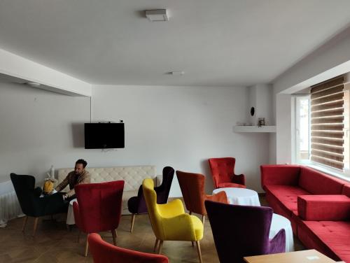 a man sitting at a table in a room with red and yellow chairs at Residence Mahala in Sarajevo