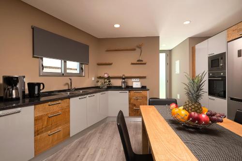 a kitchen with a table with a bowl of fruit on it at Villa da Silva (Heated Pool and Private Parking) in Arco da Calheta