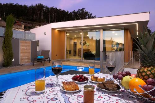 a table with food and glasses of wine on a patio at Villa da Silva (Heated Pool and Private Parking) in Arco da Calheta