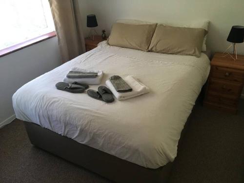 a bed with shoes and two remotes on it at Entire 2 bed apartment - Up to 4 guest - 10 min from station and town centre in Wokingham
