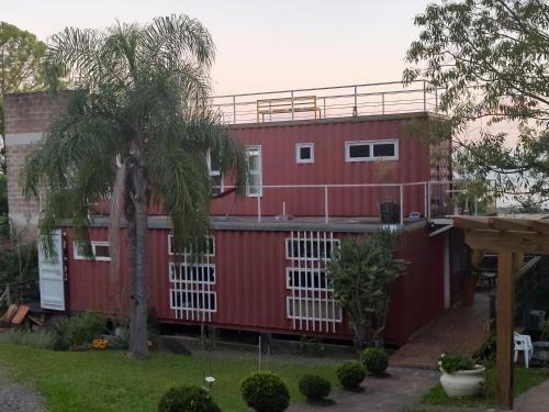 ein rotes Haus mit einer Palme davor in der Unterkunft Casa Container in Santo Antônio