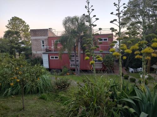 einen Garten mit einem roten Haus im Hintergrund in der Unterkunft Casa Container in Santo Antônio