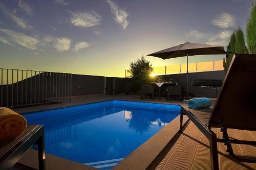 a swimming pool with a table and an umbrella at Villa da Silva (Heated Pool and Private Parking) in Arco da Calheta