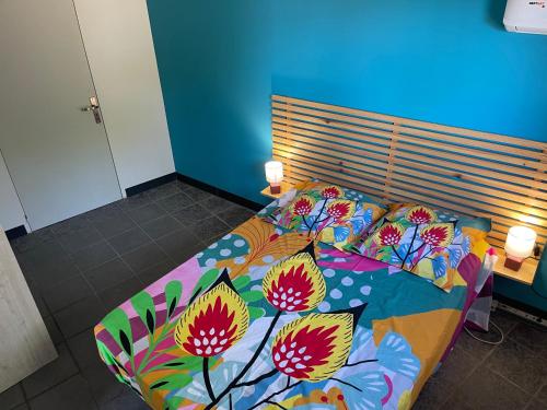 a bed with a colorful comforter with flowers on it at Kazabasté, escapade spa et jardin privatif in Basse-Terre