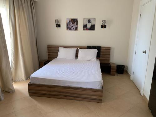 a bedroom with a bed with white sheets and photos on the wall at Sunset pearl Sahl Hashesh in Hurghada