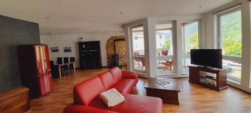 a living room with a red couch and a tv at Ferienwohnung Aroma Moselblick in Burgen