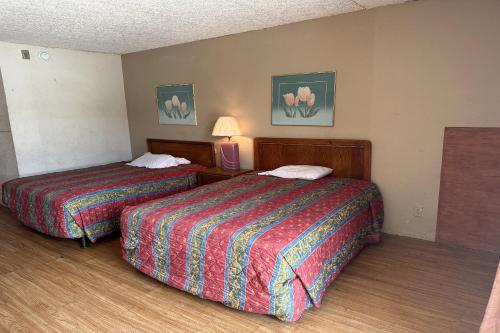 a hotel room with two beds and a lamp at Kampus Inn by OYO Gainesville - University Area in Gainesville