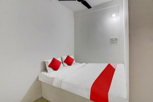 um quarto branco com uma cama com almofadas vermelhas em OYO Flagship Kings Hotel em Nagpur