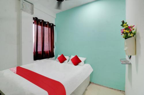 um quarto com uma cama branca e almofadas vermelhas em OYO Flagship Kings Hotel em Nagpur