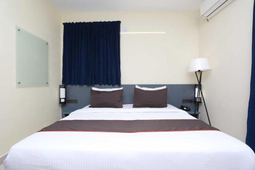 Cama blanca grande en habitación con ventana azul en Hotel Vastukar Retreat, en Bhubaneshwar