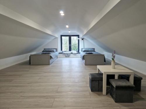 a attic room with two beds and a table at Dom nad Stryszawką z SAUNĄ - domek wypoczynkowy in Stryszawa