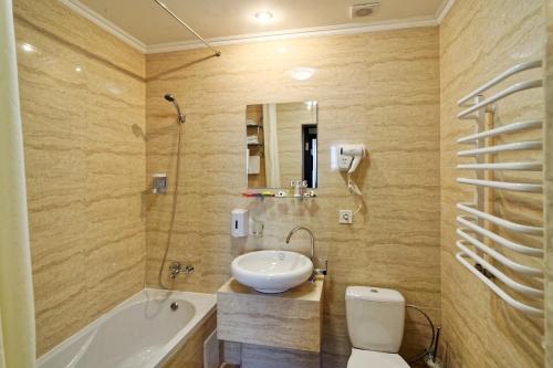 a bathroom with a sink and a tub and a toilet at Lisova Pisnia Resort Hotel in Truskavets
