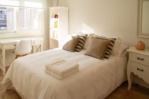 a white bed with a pile of towels on it at Bonito y luminoso apartamento en Rosalía de Castro in Santiago de Compostela