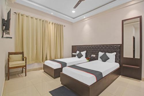 a bedroom with two beds and a chair and a mirror at Townhouse Centre Point Inn Near Esplanade Metro Station in Kolkata