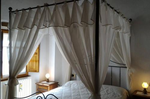 a bedroom with a canopy bed with white curtains at Casa in Borgo Medievale in Toscana in Monterone