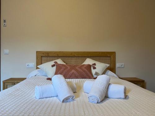 Una cama con tres toallas enrolladas. en Can Calau de Centenys, en Esponellá