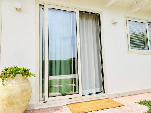 a sliding glass door with a plant in a vase at Plemmirio Apartments in Siracusa