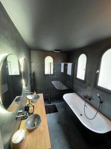 La salle de bains est pourvue d'une grande baignoire, d'un lavabo et d'une baignoire. dans l'établissement Villa&spa 3 ch 6pers en ville 12 mn de la plage, à Montpellier
