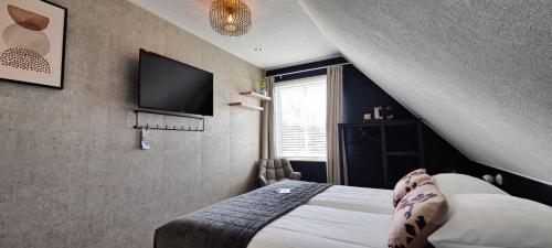 a bedroom with a bed and a flat screen tv at Pension Bakema Ameland in Nes