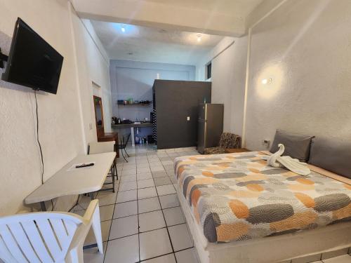 a room with a bed and a table and a television at Small studio APT 5min to DT! in Zihuatanejo