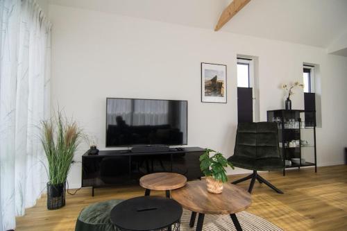 uma sala de estar com uma televisão e uma mesa e cadeiras em Ferienhaus mit Zugang zum Wasser em Anjum