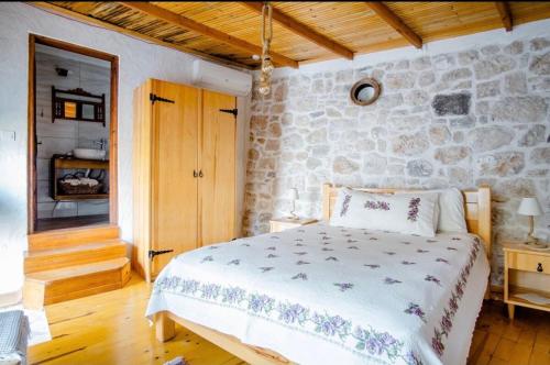 a bedroom with a bed and a stone wall at Saklı Konak in Karaburun