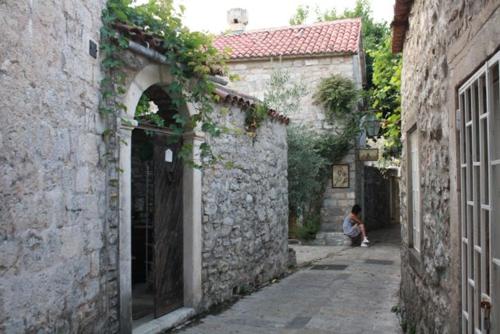 a person sitting in an alley between two buildings at Best Location Old Town Budva Rooms in Budva