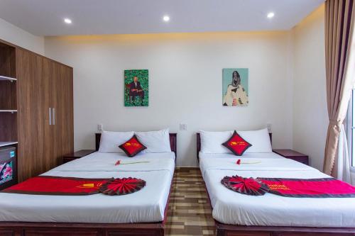 two beds in a room with white walls and red accents at Le House Hotel and Studio in Danang