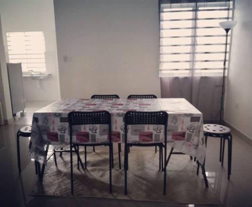 a dining room table with four chairs and a tablecloth at #Guest House near Hub Education University Pagoh in Muar