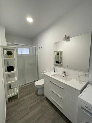 a white bathroom with a toilet and a sink at Acogedor bungalow con vistas in Puerto de la Cruz