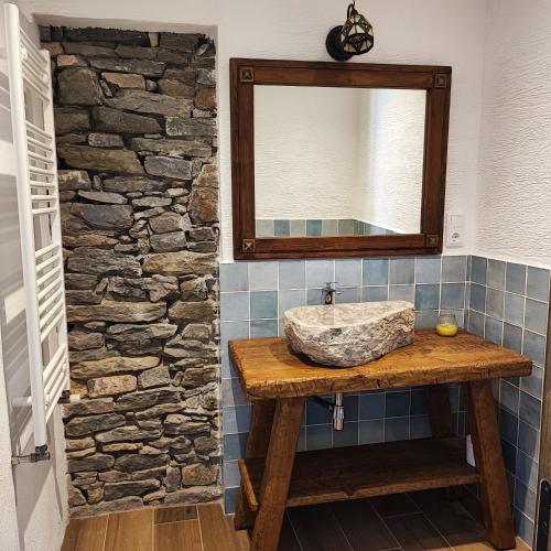uma casa de banho com um lavatório e um espelho numa parede de pedra em Allotjament Sant Joan de Fabregues - Rupit i Pruit em Rupit