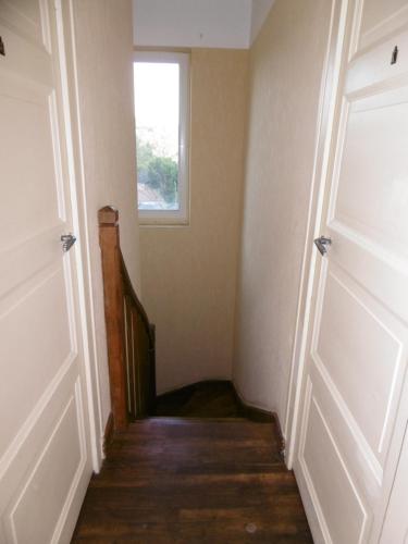 un couloir vide avec une porte et une fenêtre dans l'établissement Appartement pour 3 personnes à Sarlat, à Sarlat-la-Canéda