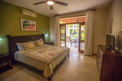 a bedroom with a bed and a television and a balcony at Club del Cielo Condominium Rental in Jacó