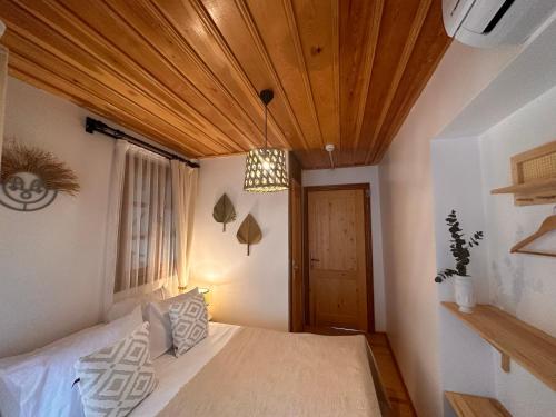 a bedroom with a bed with a wooden ceiling at Hanole Guest House in Ayvalık