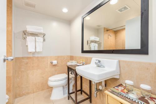a bathroom with a sink and a toilet and a mirror at CASTLE at Palms at Waikīkī in Honolulu