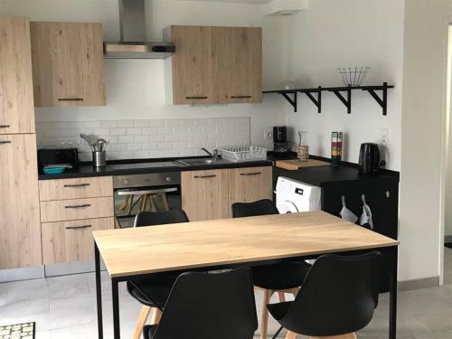 uma cozinha com uma mesa de madeira e cadeiras pretas em Appartement avec jardin privatif em Lorient