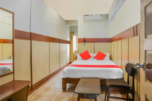 Schlafzimmer mit einem Bett mit roten Kissen und einem Tisch in der Unterkunft Flagship Sai Vishram in Bangalore